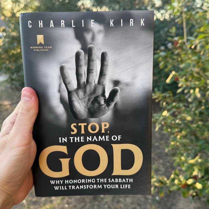 Stop, in the Name of God by Charlie Kirk — book cover held outdoors in Austin, Texas