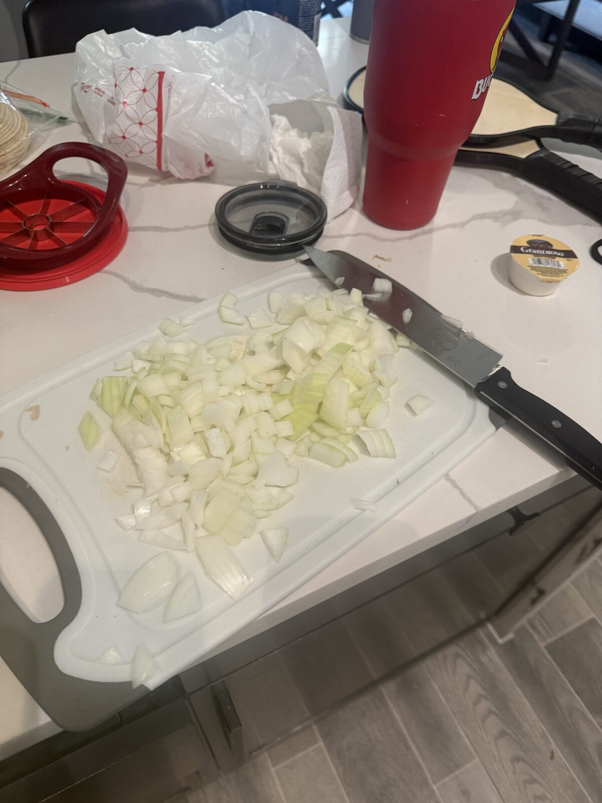 Diced yellow onion on a white cutting board, ready to sauté